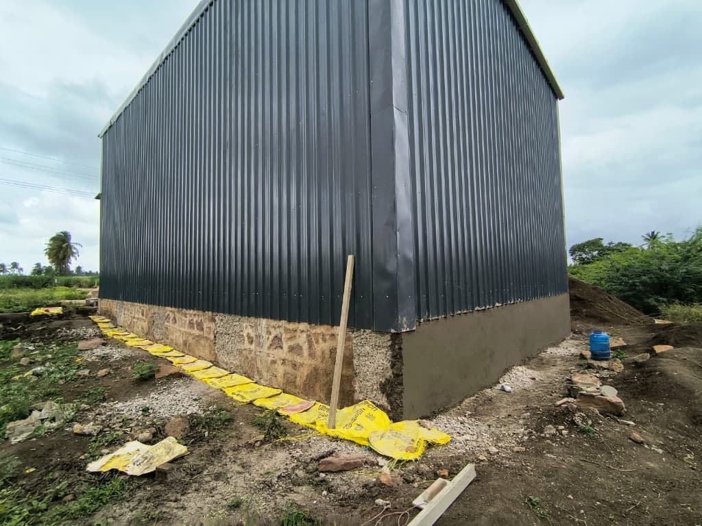 KM Construction industrial shed with metal cladding and stone foundation during construction
